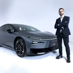 Elegancki mężczyzna w garniturze stoi obok szarego XPeng P7.