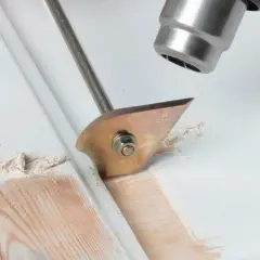 Strumento per rimuovere pittura secca dal legno, con lama affilata che solleva schegge di vernice.