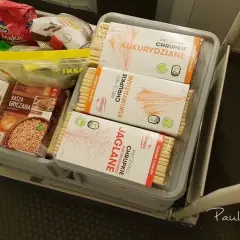 Koszyk z produktami długoterminowymi: kasza gryczana, chrupki kukurydziane i jaglane.