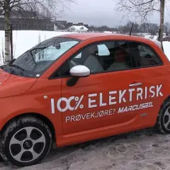 Pomarańczowy Fiat 500e w zimowej scenerii, z napisem "100% ELEKTRISK". Sprawdź zasięg tego elektryka!
