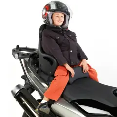 Niño sonriente con casco en asiento de moto. ¿A qué edad puede ir un niño en moto? Depende de la normativa y el equipo.