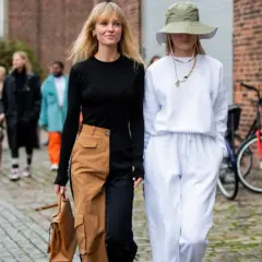Deux femmes marchent, l'une porte un pantalon bicolore audacieux, l'autre un ensemble blanc décontracté.