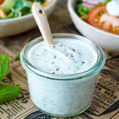 Cremiges Joghurt Dressing mit Kräutern in einem Glas, bereit für einen frischen Salat.
