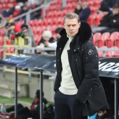 Trener GKS Tychy w zimowej kurtce, analizuje sytuację na boisku, myśląc o przyszłych gks tychy transfery.