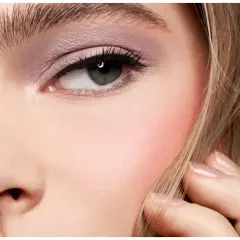 Un occhio truccato con ombretto rosa e un tocco di blush sulle guance, che dona un aspetto sano e radioso.