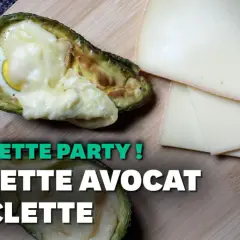 Avocat farci d'un œuf et de fromage fondu, une recette de raclette sans pomme de terre, avec des tranches de fromage à côté.