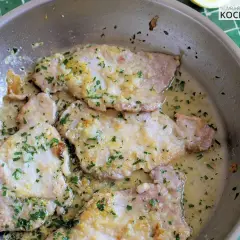 Zarte Scaloppine al Limone in einer Pfanne, garniert mit frischer Petersilie und Zitronenschale. Ein Klassiker der italienischen Küche.