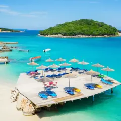 Albania jakie morze? Turkusowa woda, piaszczysta plaża, leżaki i parasole na drewnianym pomoście. Idealne miejsce na wakacje.