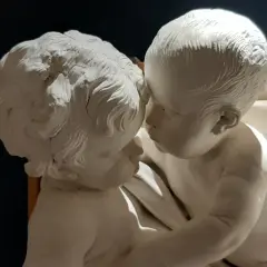 Due putti in stucco, un'opera di Giacomo Serpotta, si abbracciano teneramente.