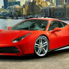 Czerwone Ferrari 488 GTB z dumą prezentuje się na tle Londynu, z Tower Bridge w tle.