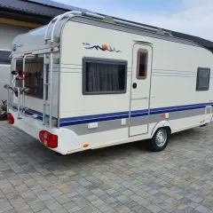 Biała przyczepa kempingowa Hobby 460 UFE z bagażnikiem rowerowym z tyłu, gotowa na wakacyjne przygody.