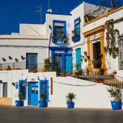 Casas blancas con puertas y ventanas azules, un ejemplo de lo que ver cerca de Níjar. Plantas en macetas adornan las fachadas.