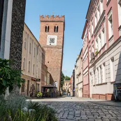 Wieża zegarowa w Ząbkowicach Śląskich na tle kamienic i brukowanej ulicy.