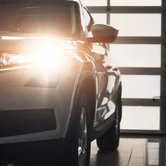 Biały SUV z włączonymi światłami pozycyjnymi i postojowymi, gotowy do jazdy.
