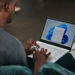 Mężczyzna na laptopie z systemem Windows 11, szukający informacji, jak zmienić nazwę użytkownika Windows 11.