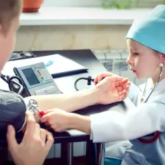 Dziecko w stroju lekarza mierzy ciśnienie. Czy tauryna podnosi ciśnienie? To pytanie, na które odpowiedzi szukają mali medycy.