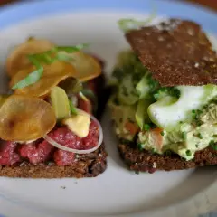 Dos sándwiches abiertos, uno con tartar de ternera y patatas fritas, otro con ensalada de pollo y pepino. Comida típica de Dinamarca.