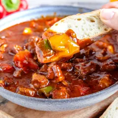 Herzhaftes Schaschliktopf Rezept: Fleischstücke und Paprika in würziger Sauce, perfekt zum Dippen mit Brot.