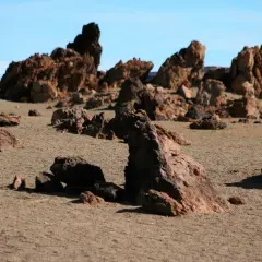 Paisaje desértico con rocas volcánicas rojizas y arena, evocando la zona de las minas de San José.
