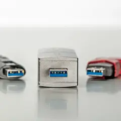 Fünf USB-Sticks in verschiedenen Designs, alle mit blauem Anschluss. Einer davon, der mittlere, wirkt besonders robust, fast wie ein Relikt aus der Zeit der USB 1.0 Geschwindigkeit.