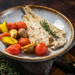 Delicioso abadejo a la plancha servido con patatas asadas y tomates cherry.