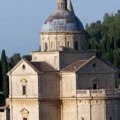Il tempio di San Biagio, con la sua imponente cupola e la facciata in pietra, si erge maestoso tra i cipressi toscani.