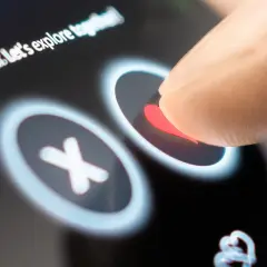 Palec dotyka serca na ekranie telefonu, wybierając potencjalną randkę. Aplikacje randkowe na telefon ułatwiają poznawanie nowych ludzi.