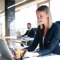 Eine Frau am Laptop, die die master digitalisierung vorantreibt. Im Hintergrund ein Kollege.