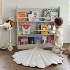 Chłopiec wybiera książkę z regału, tworząc przytulną przestrzeń do nauki i zabawy. Idealne miejsce na montessori w domu.