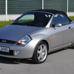 Srebrny Ford Streetka z czarnym dachem, zaparkowany na ulicy.