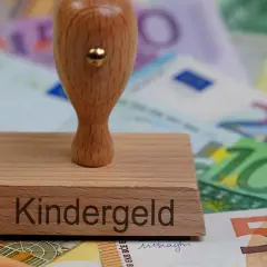 Stempel z napisem "Kindergeld" na tle banknotów euro. To symbol wsparcia dla rodzin, jak 500+.