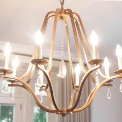 A golden chandelier with crystal drops hangs from the ceiling, illuminating the dining room. The dining room chandelier height is perfect for the space.