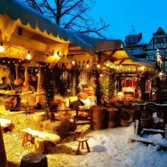 Winterliche Kirmes Gummersbach: Ein festlich beleuchteter Stand mit Körben und Holzwaren im Schnee.