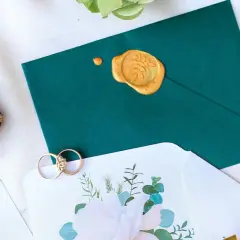 Elegancka koperta z pieczęcią, obrączki i zaproszenie. Zastanawiasz się, nie idę na wesele ile dać do koperty?