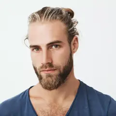 Hombre con barba y moño, luciendo unas modernas mechas rubias que resaltan su estilo.
