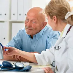 Lekarka omawia z pacjentem najnowsze leki na prostatę, wskazując na ekran komputera.