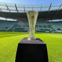 Trofeum Ligi Konferencji Europy UEFA błyszczy na tle pustego stadionu.