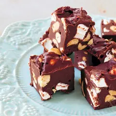 Chokladbitar med marshmallows och nötter, en härlig rocky road-fudge på en ljusblå tallrik.