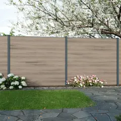 Moderne gartenzaun ideen bilder: Ein Sichtschutzzaun aus Holzoptik mit anthrazitfarbenen Pfosten, umgeben von blühenden Sträuchern und einem gepflegten Rasen.