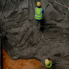 Pracownicy wylewają beton na strop monolityczny. Kluczowe są wymagania konstrukcyjne dla betonu B20 lub B25.