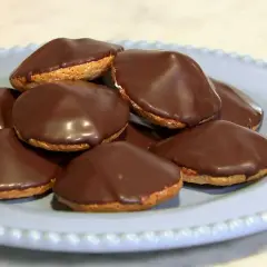 En hög med chokladöverdragna biskvier på en ljusblå tallrik. Perfekt för ett enkelt biskvier recept.