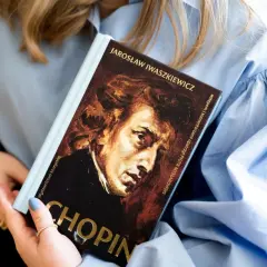 Książka o Chopinie, jednym z najwybitniejszych polskich kompozytorów, w rękach kobiety.