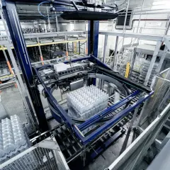 Automatyczny system pakowania butelek z wodą w nowoczesnym gnieździe produkcyjnym.