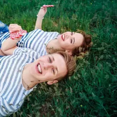 Para, która leży na trawie, trzymając lizaki. Ich uśmiechy sugerują, że mają otwarty związek, co to znaczy?