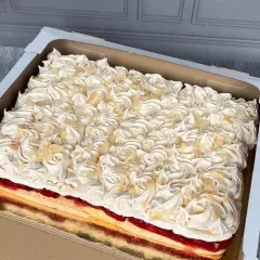 Prostokątny tort w pudełku, pokryty kremem i płatkami migdałów. Piękne dekoracje tortów, które zachwycają.