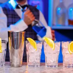 Barman przygotowuje drinki. Zastanawiasz się, ile kosztuje kurs barmanski? Zobacz, jak powstają drinki z lodem i pomarańczą.
