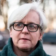 Joanna Kluzik Rostkowska w okularach i zielonym swetrze, z siwymi włosami.
