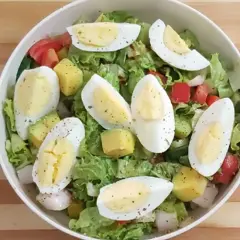 Salade colorée avec avocat, œuf dur coupé en quartiers, tomates, concombres et laitue. Un délice frais et équilibré.