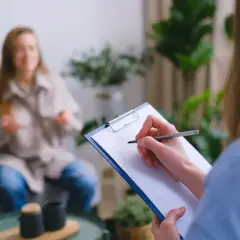 Psycholog policyjny zarobki: sesja terapeutyczna z pacjentem, notatki na kartce.