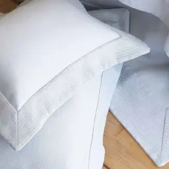 Close-up of white pillow shams with decorative borders, often used to dress up a bed and protect pillows.
